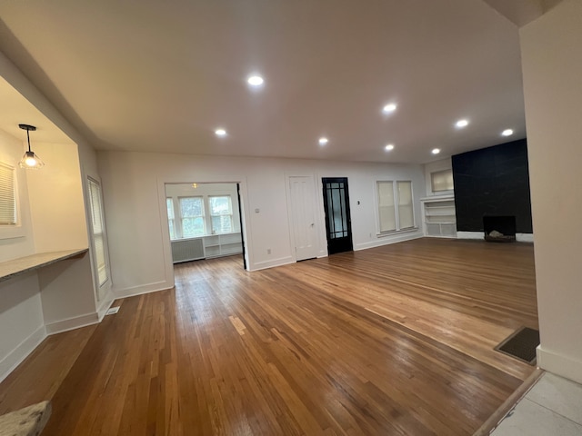 unfurnished living room with radiator and wood-type flooring