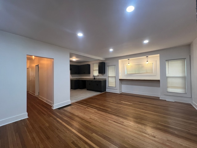 unfurnished living room featuring sink and dark hardwood / wood-style flooring