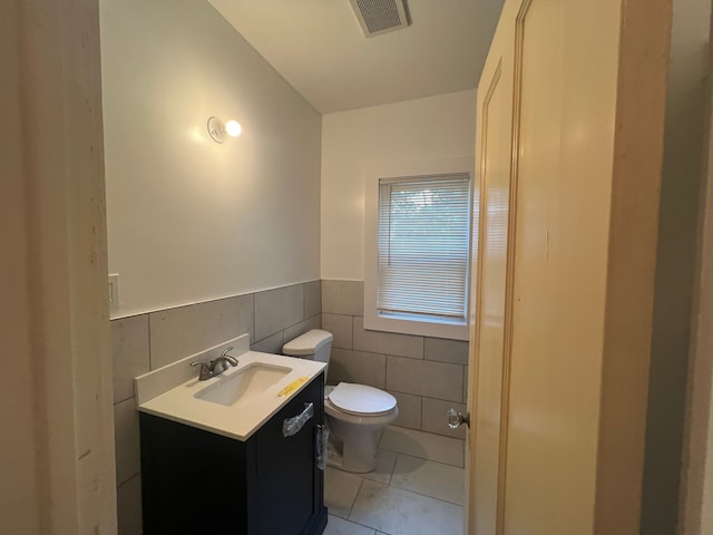 bathroom with vanity, toilet, tile patterned flooring, and tile walls