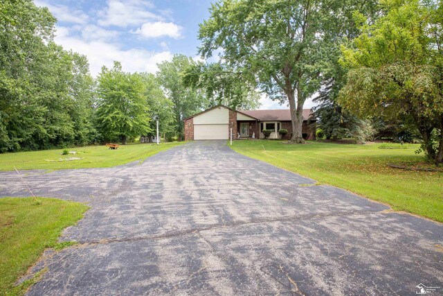 28237 W Huron River Dr, Huron, MI 48134 - view of front of property with a front yard, driveway, brick siding, and a garage