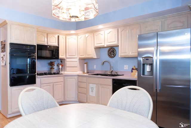 kitchen with light wood-type flooring, sink, an inviting chandelier, and black appliances