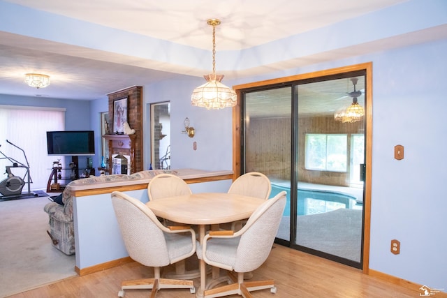 dining room featuring a brick fireplace, a notable chandelier, and light hardwood / wood-style flooring