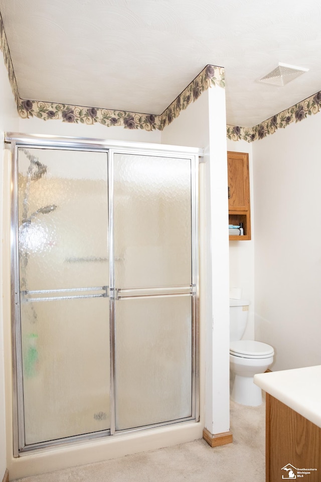 bathroom featuring vanity, toilet, and a shower with door