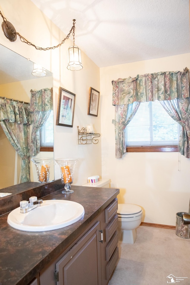 bathroom with vanity, toilet, and a textured ceiling