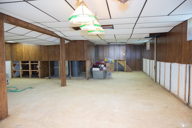 basement with a paneled ceiling and wooden walls