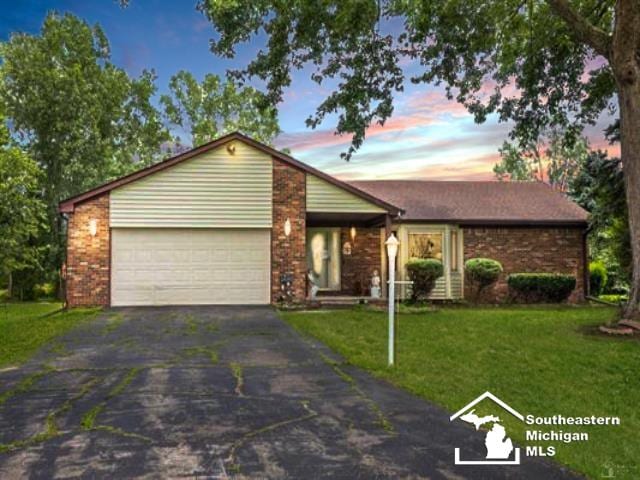 28237 W Huron River Dr, Huron, MI 48134 - view of front facade featuring asphalt driveway, an attached garage, a lawn, and brick siding