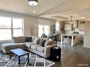 living room with plenty of natural light, dark hardwood / wood-style floors, and a raised ceiling