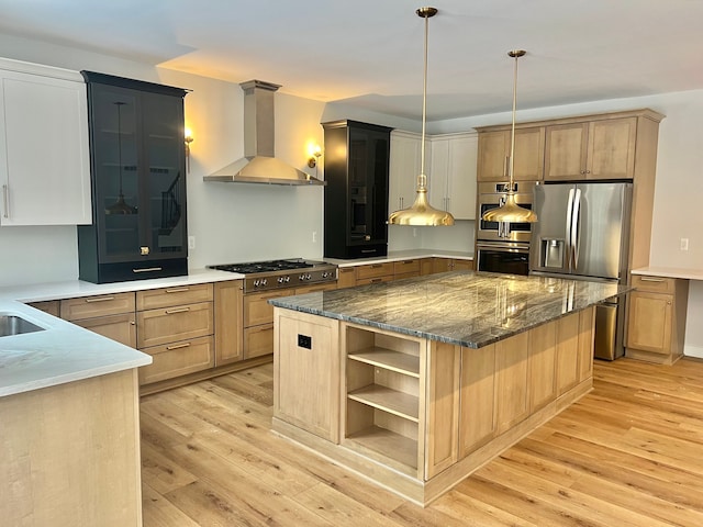 kitchen with dark stone counters, light wood-style floors, stainless steel appliances, wall chimney range hood, and open shelves