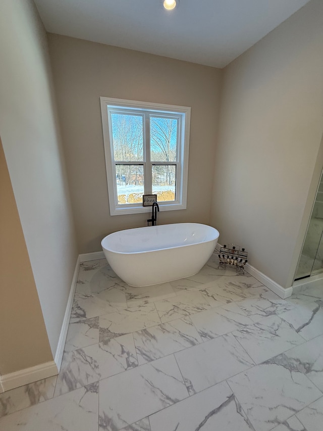 full bath featuring marble finish floor, a shower with shower door, a freestanding tub, and baseboards