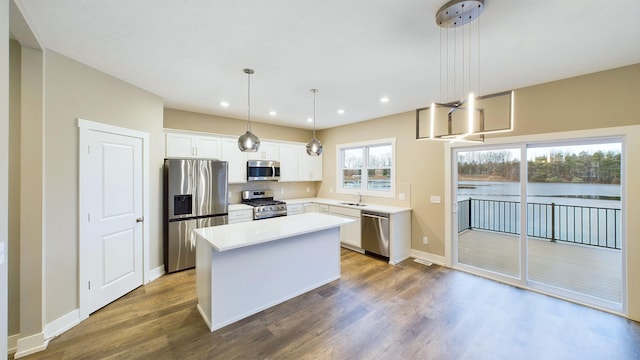 kitchen with a kitchen island, dark wood-style floors, stainless steel appliances, white cabinets, and light countertops