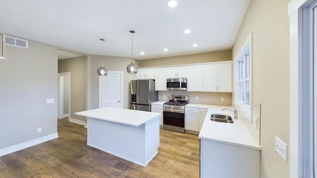 kitchen featuring a sink, tasteful backsplash, a kitchen island, appliances with stainless steel finishes, and light wood finished floors