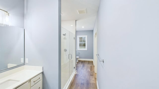 bathroom featuring vanity, wood finished floors, visible vents, a stall shower, and toilet