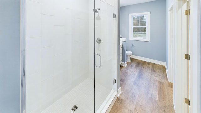 bathroom featuring a stall shower, toilet, baseboards, and wood finished floors