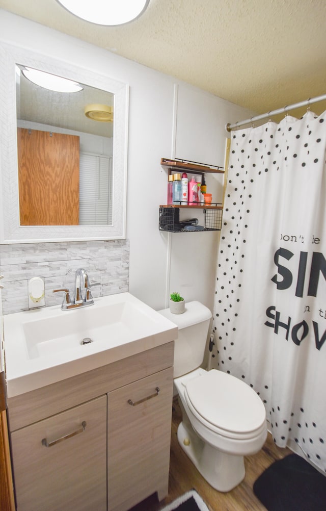 bathroom with vanity, backsplash, toilet, a textured ceiling, and wood-type flooring