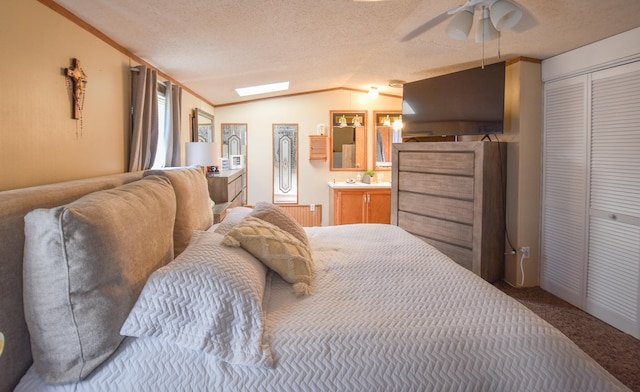 bedroom featuring ceiling fan, lofted ceiling with skylight, a textured ceiling, a closet, and carpet