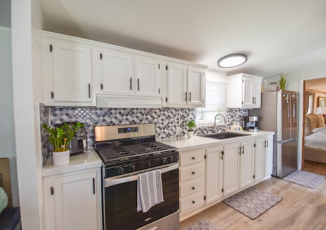 kitchen featuring white cabinetry, sink, tasteful backsplash, appliances with stainless steel finishes, and light wood-type flooring