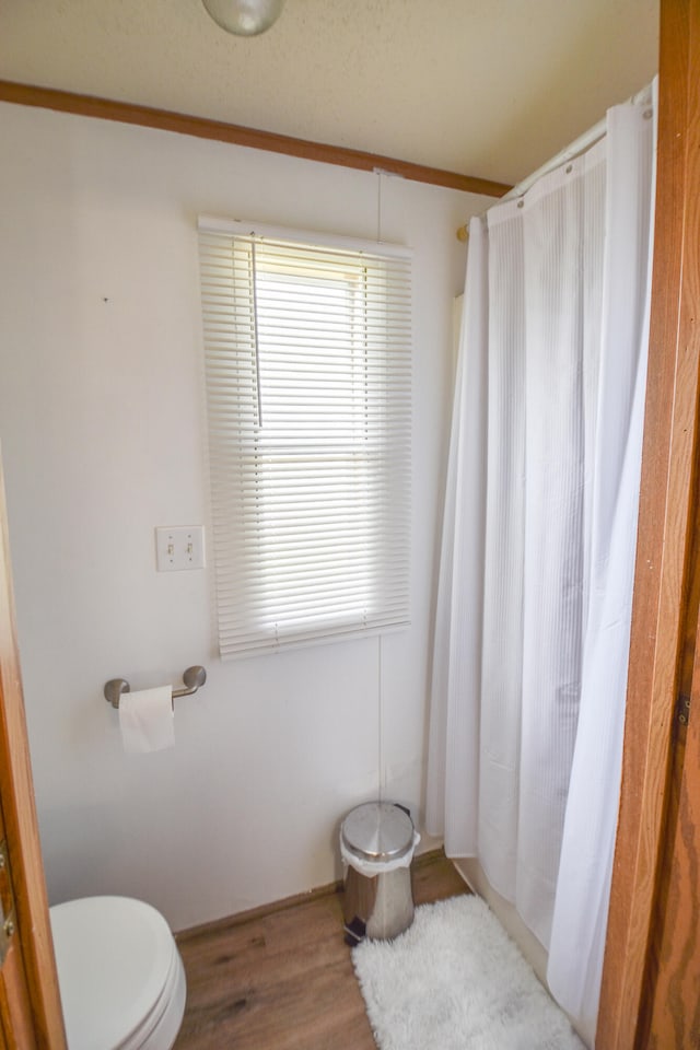 bathroom featuring hardwood / wood-style floors, toilet, and crown molding