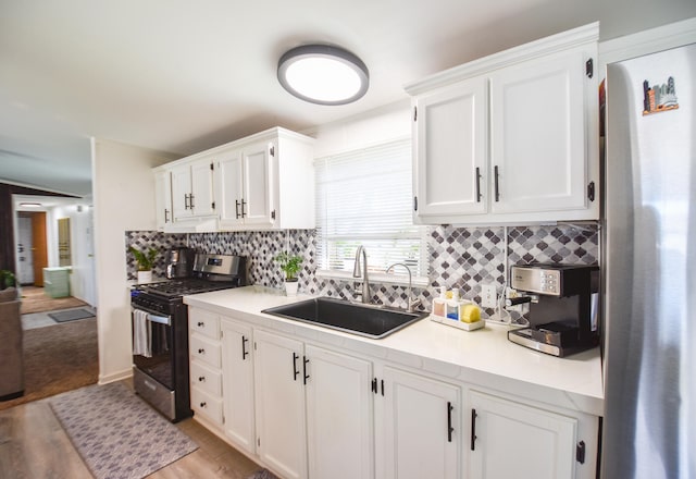 kitchen with appliances with stainless steel finishes, light wood-type flooring, white cabinetry, and sink