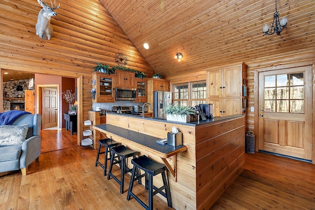 kitchen with high vaulted ceiling, stainless steel appliances, a wealth of natural light, and light hardwood / wood-style flooring