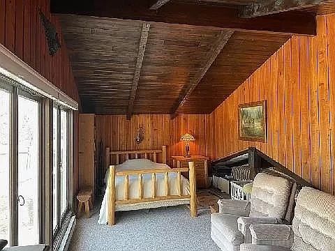 bedroom featuring vaulted ceiling with beams, wood walls, carpet, and wooden ceiling