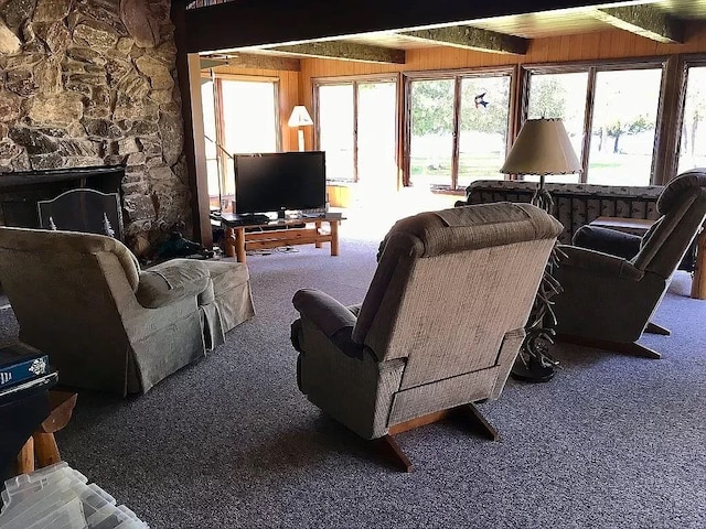 living room featuring beamed ceiling, wood walls, and carpet floors