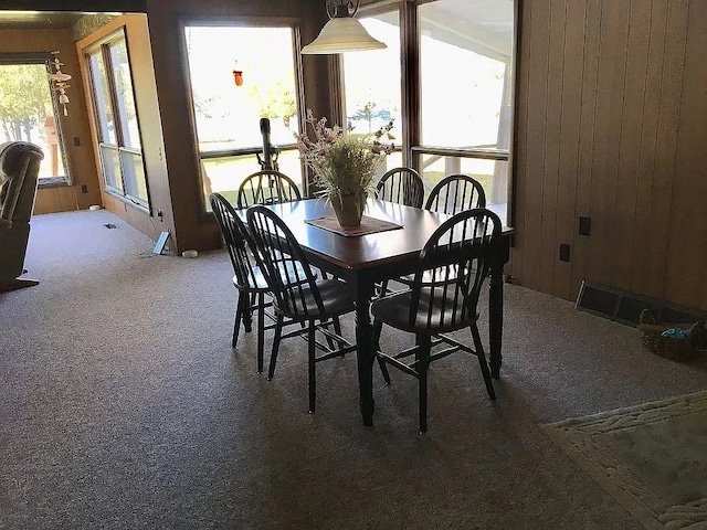 carpeted dining room with wood walls