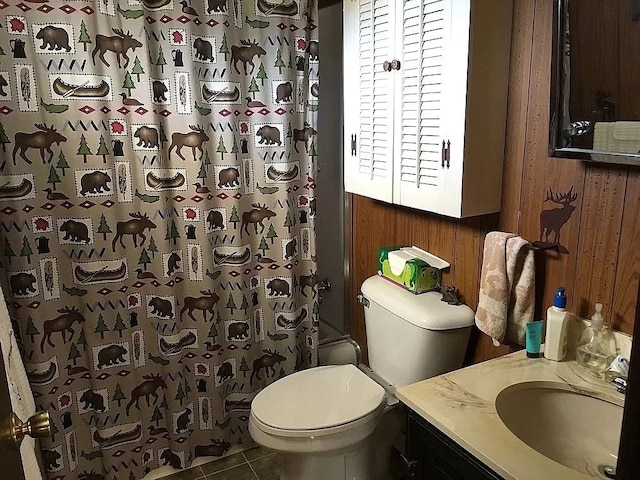 bathroom featuring vanity, wooden walls, tile patterned flooring, toilet, and walk in shower