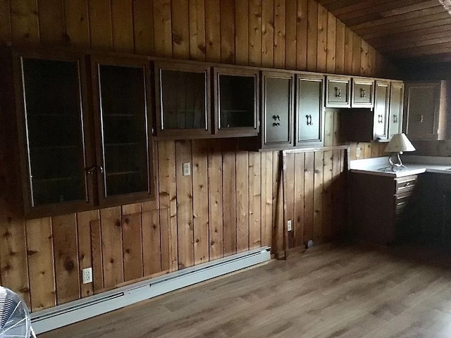 kitchen featuring a baseboard heating unit, wood-type flooring, lofted ceiling, wooden walls, and wood ceiling