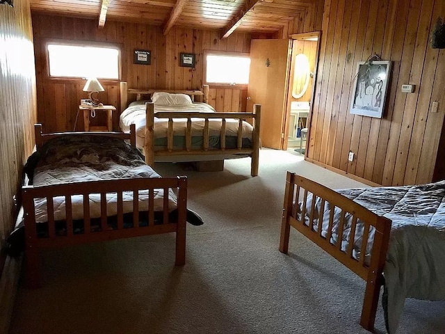 carpeted bedroom with beamed ceiling, wooden ceiling, and wood walls