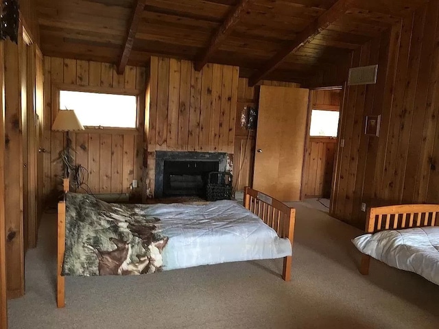 carpeted bedroom featuring beam ceiling, wooden walls, and wooden ceiling