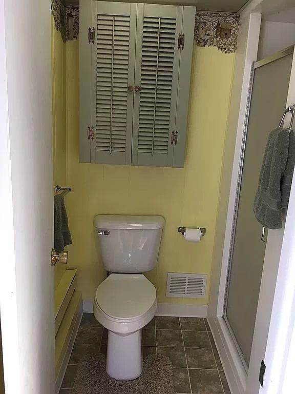 bathroom featuring tile patterned floors, toilet, and a shower with door