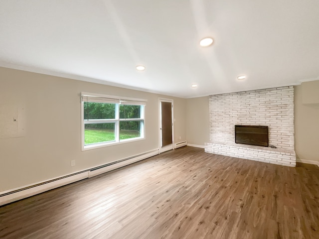 unfurnished living room with hardwood / wood-style floors, crown molding, baseboard heating, and a fireplace