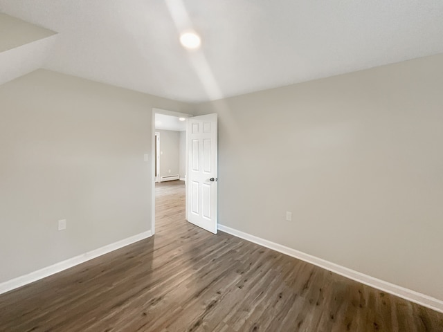 interior space with baseboard heating, dark wood-type flooring, and vaulted ceiling