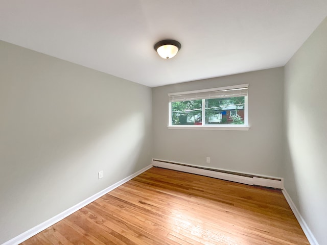 empty room featuring hardwood / wood-style flooring and a baseboard radiator