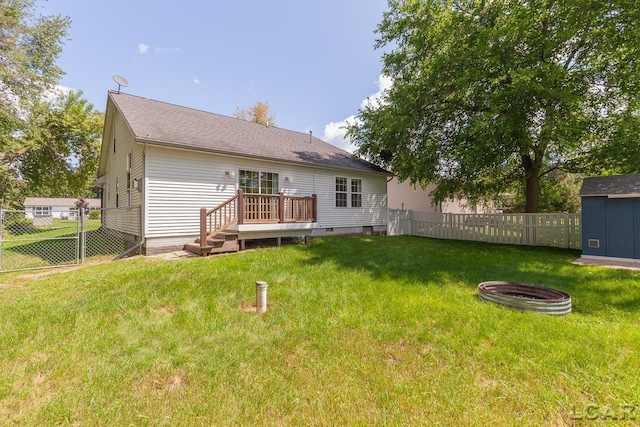 back of house with a fire pit, a storage unit, a wooden deck, and a lawn