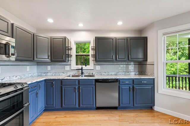 12171 Grandview Dr, Jerome, MI 49249 - kitchen featuring appliances with stainless steel finishes, tasteful backsplash, light wood-style floors, a sink, and blue cabinets