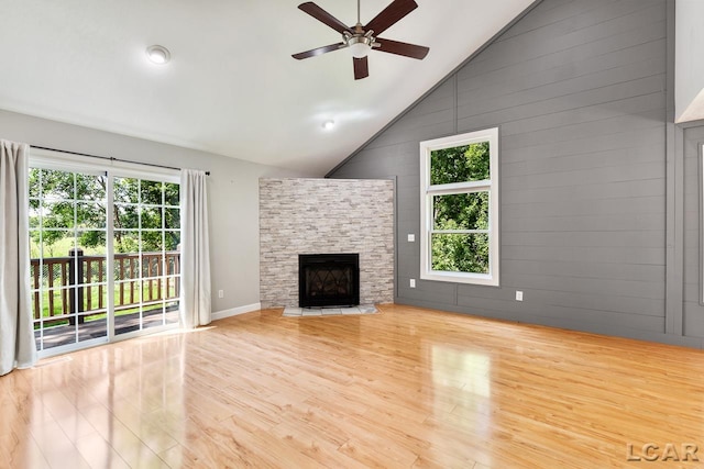 unfurnished living room with a wealth of natural light, a fireplace, ceiling fan, and light wood-type flooring