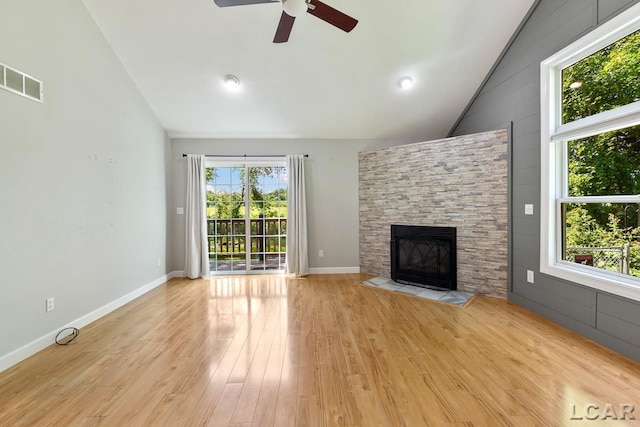 12171 Grandview Dr, Jerome, MI 49249 - unfurnished living room featuring ceiling fan, a stone fireplace, light wood finished floors, high vaulted ceiling, and baseboards