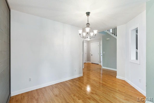 empty room with a notable chandelier and light hardwood / wood-style flooring