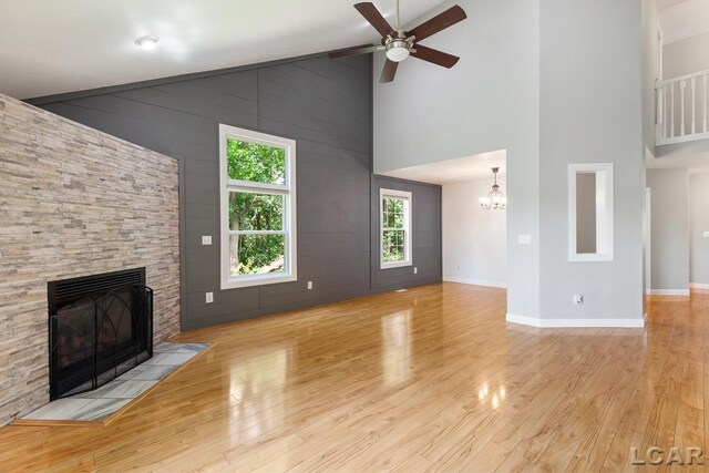 12171 Grandview Dr, Jerome, MI 49249 - unfurnished living room with high vaulted ceiling, a fireplace, wood finished floors, a ceiling fan, and a chandelier