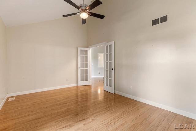 spare room featuring ceiling fan, light hardwood / wood-style floors, high vaulted ceiling, and french doors