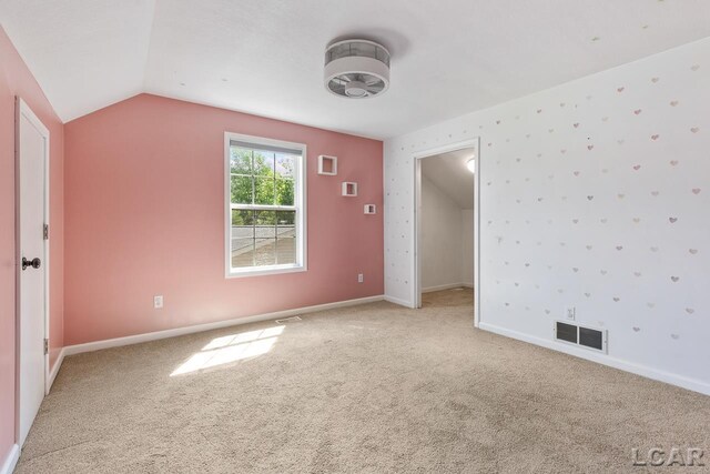 12171 Grandview Dr, Jerome, MI 49249 - spare room featuring light carpet, lofted ceiling, and baseboards