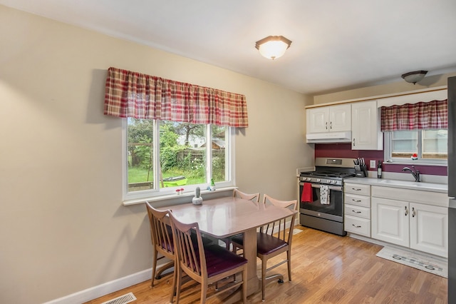 kitchen with stainless steel gas range oven, light wood-type flooring, white cabinetry, and sink