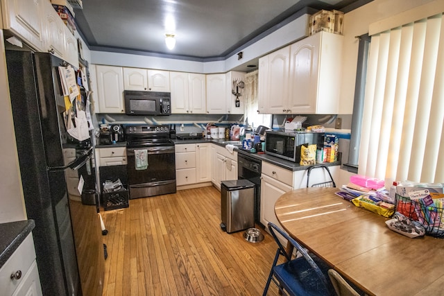 kitchen with black appliances, light hardwood / wood-style floors, white cabinetry, and sink