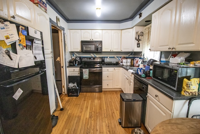 kitchen featuring black appliances, white cabinets, light wood-type flooring, and sink