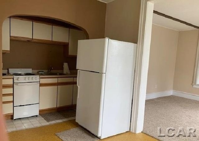 kitchen with white appliances, light colored carpet, and sink