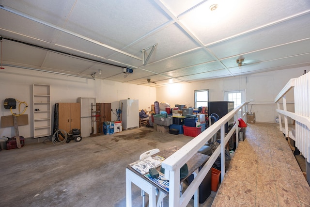 garage featuring ceiling fan, white fridge, and a garage door opener