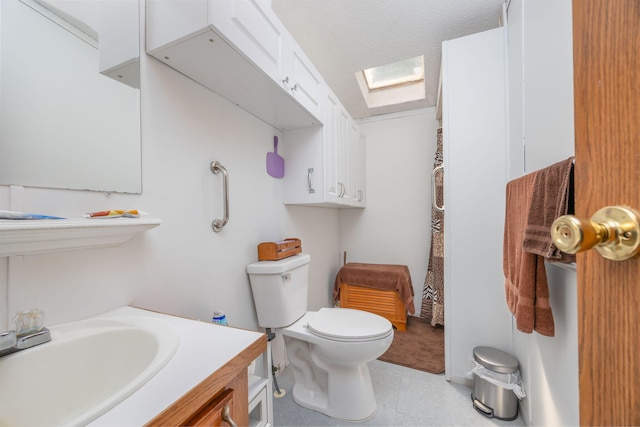 bathroom with vanity, a textured ceiling, a skylight, and toilet