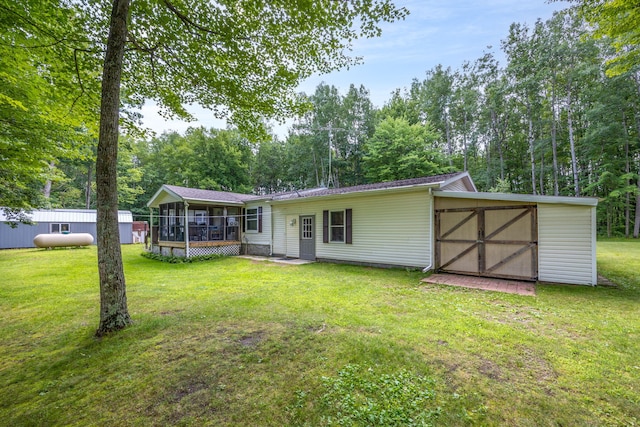 back of property with a storage unit, a lawn, and a sunroom