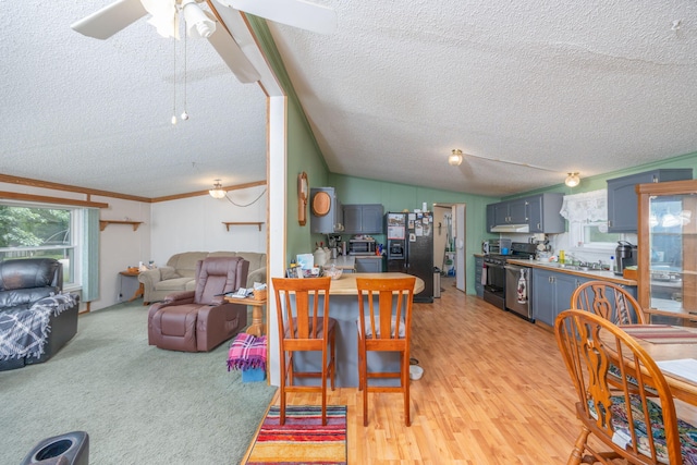 dining space featuring light wood-type flooring, ornamental molding, a textured ceiling, vaulted ceiling, and ceiling fan